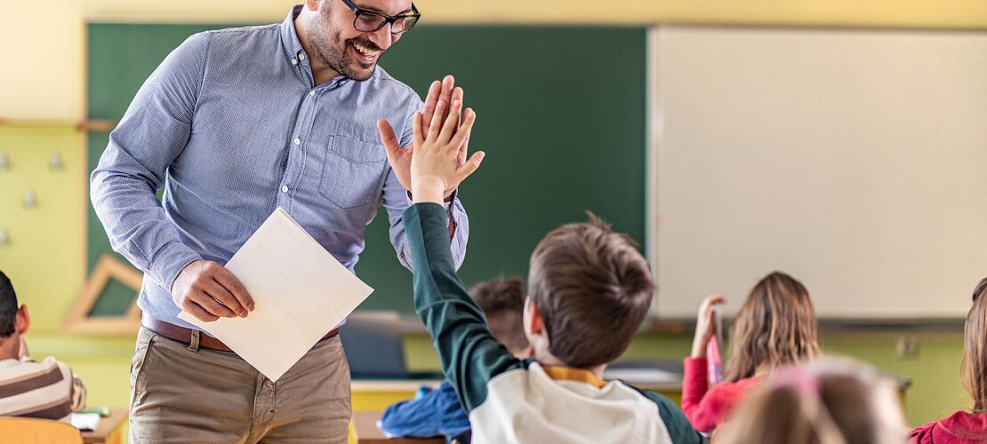 Lehrer klatscht in die Hände eines Schülers