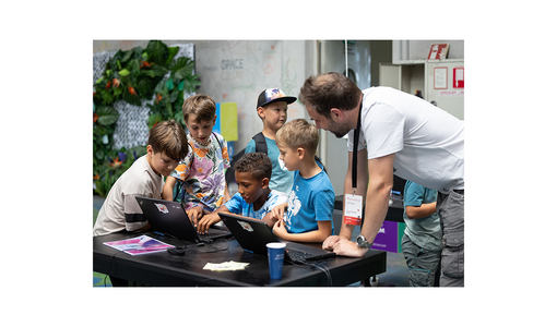 Lehrerin mit einer Gruppe von Kindern um einen Laptop herum