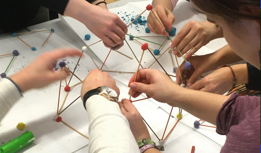 gibt eine mathematische Aufgabe mit Holzstäben und Kugeln in Rot, Weiß und Blau aus