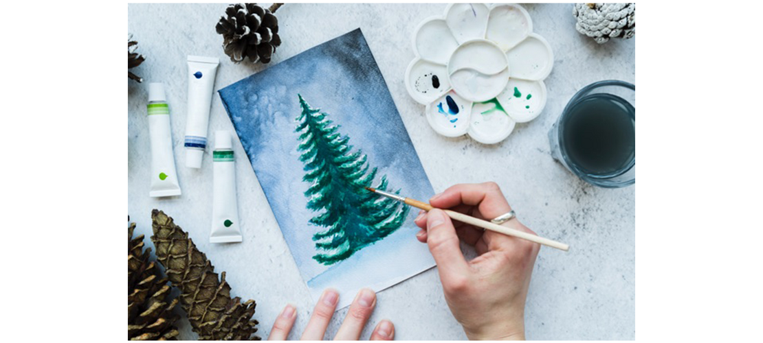 Draufsicht auf eine Frau, die von Hand einen Weihnachtsbaum auf eine Leinwand malt