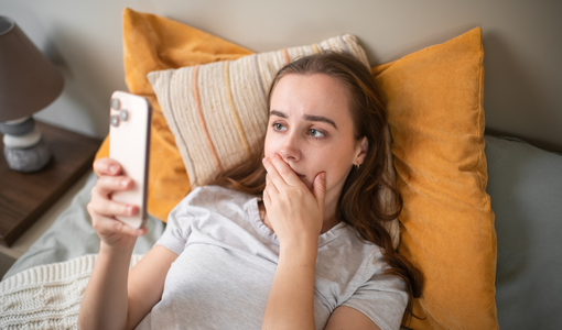 © ArtMarie/E+/Getty Images Besorgte junge Frau mit Smartphone zu Hause